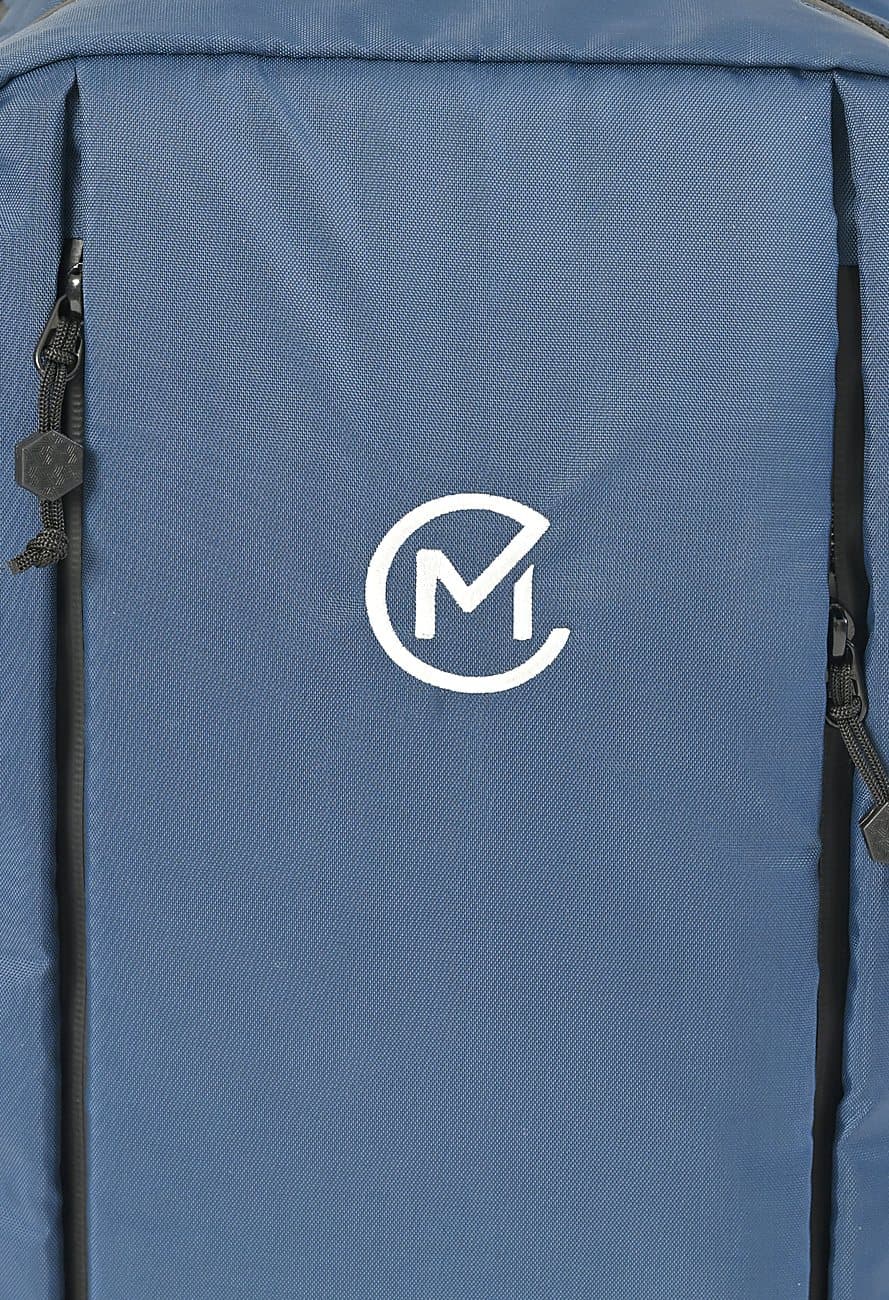 Close up of the Moda monogram embroidered in warm off-white on the navy front panel