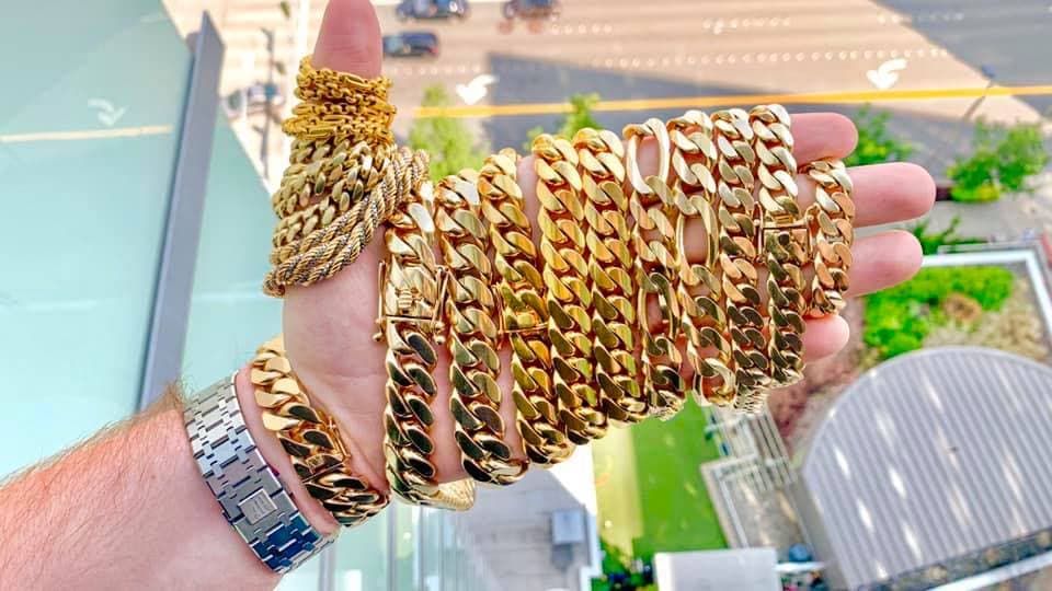 A hand holding a thick stack of gold Cuban link chains