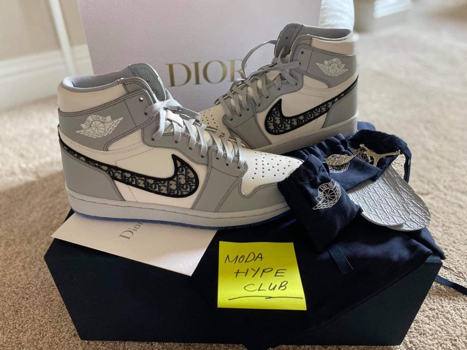 A pair of Dior Air Jordan 1 sneakers on their box with a handwritten Moda Hype Club note