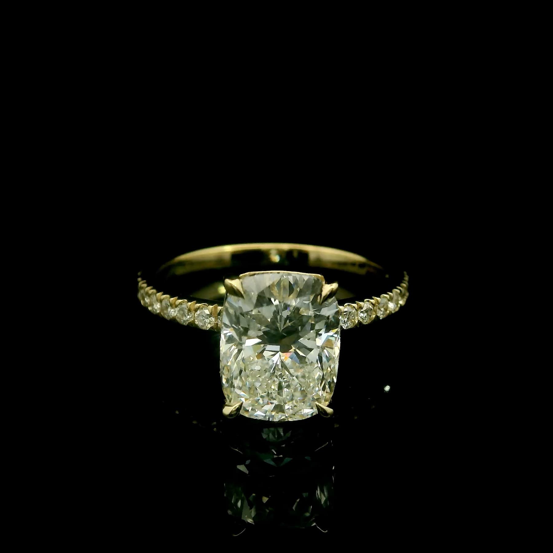 Diamond engagement ring with accent stones along the band, shot on black