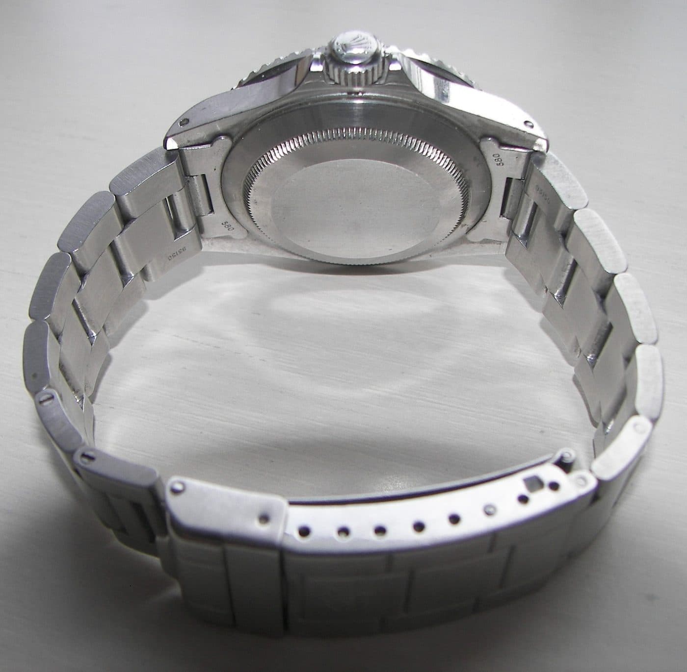Underside of a steel Rolex Submariner on an Oyster bracelet, with the end links stamped 580 and the next links stamped 93150
