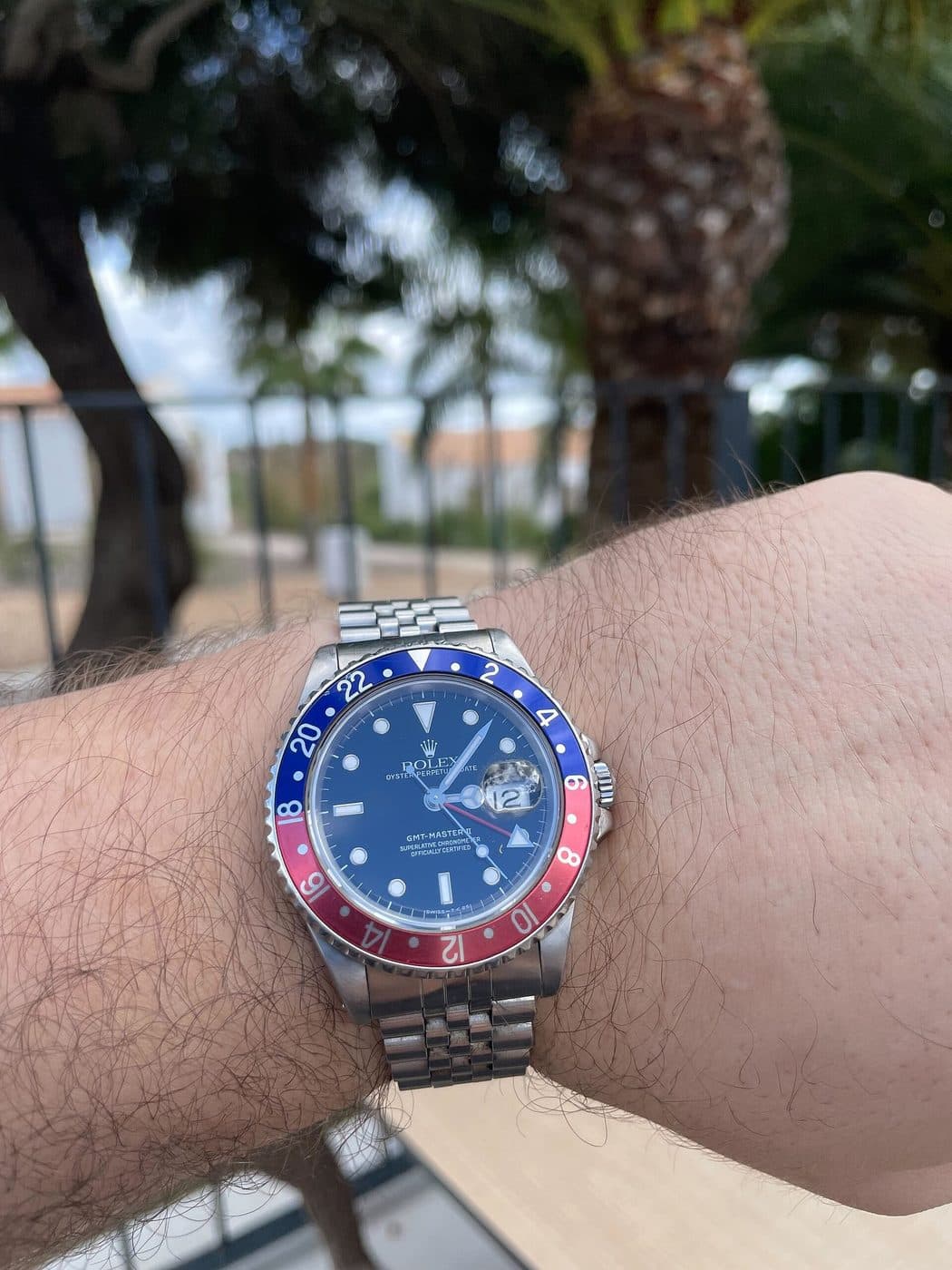 A Rolex GMT-Master II with a blue and red bezel on a steel Jubilee bracelet, worn on a wrist outdoors