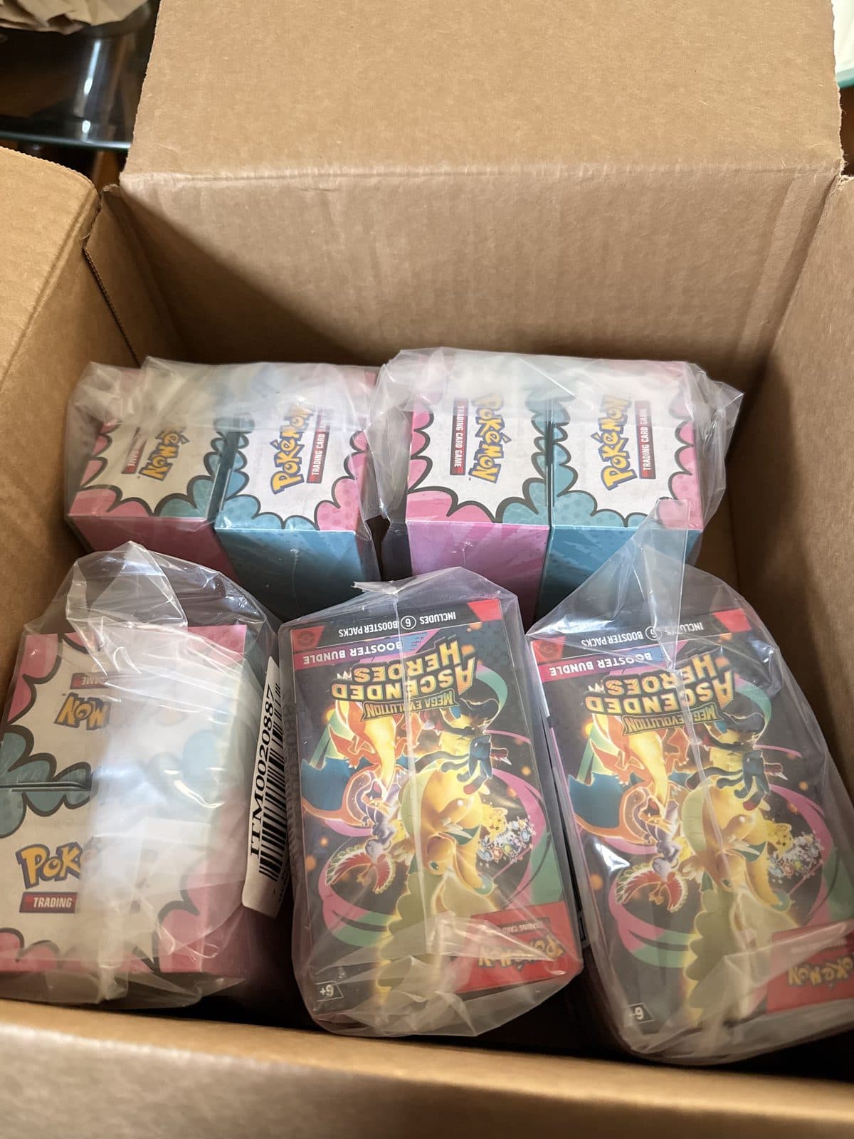 Sealed Pokemon booster bundles and boxes in plastic wrap, packed in a shipping box