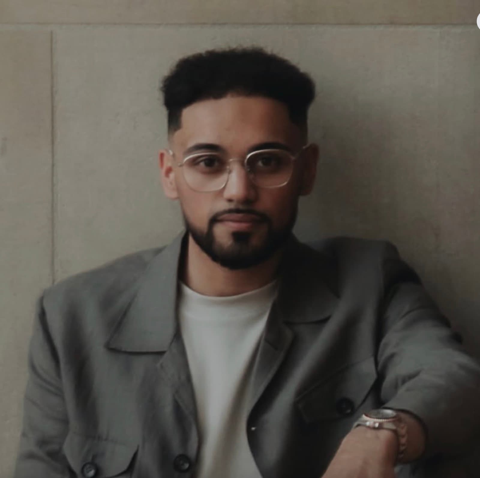 Baasit Kazi, the owner of Mistify Parfums, in a grey jacket against a neutral wall