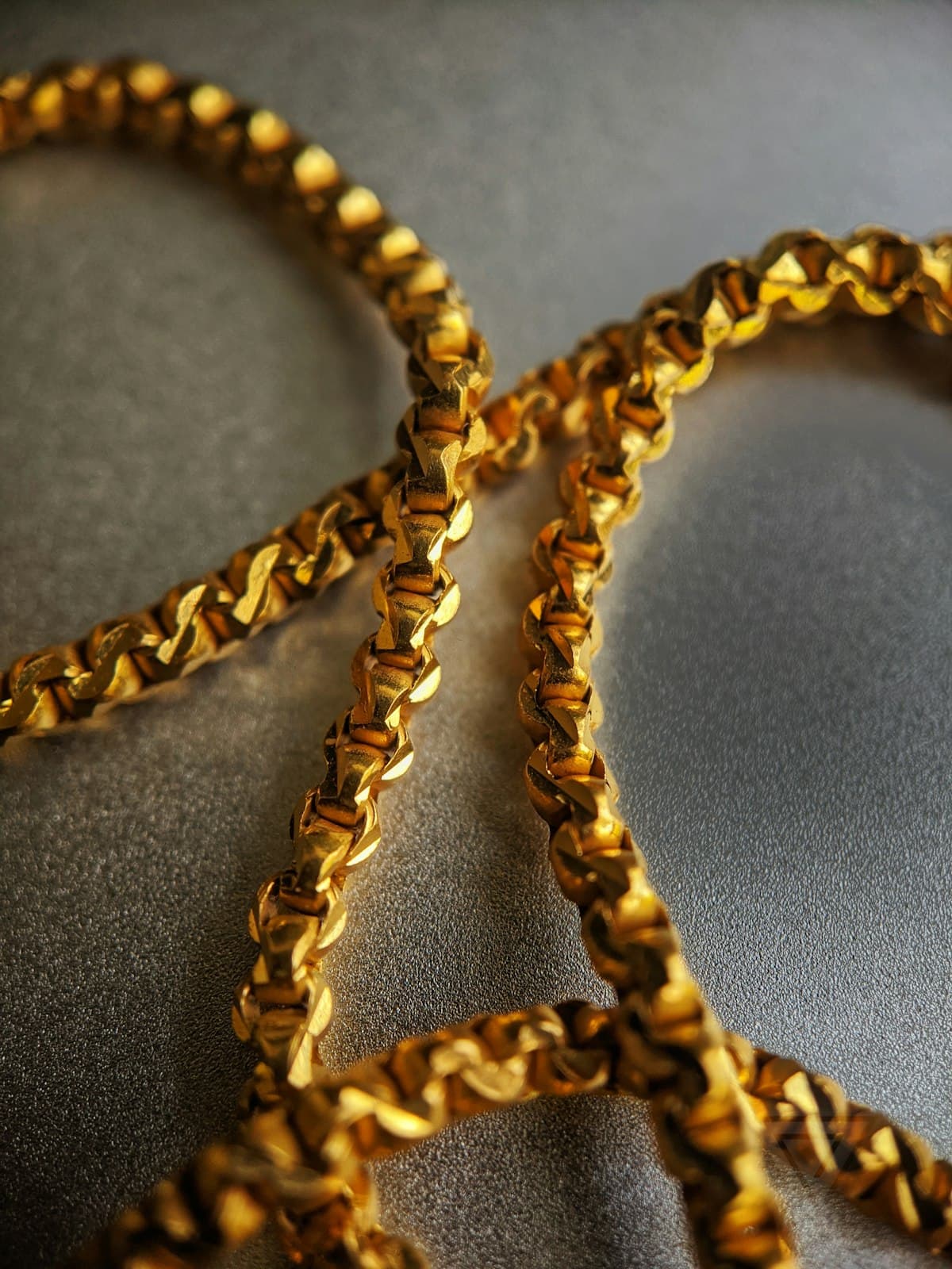 A heavy coiled gold rope chain on a dark background