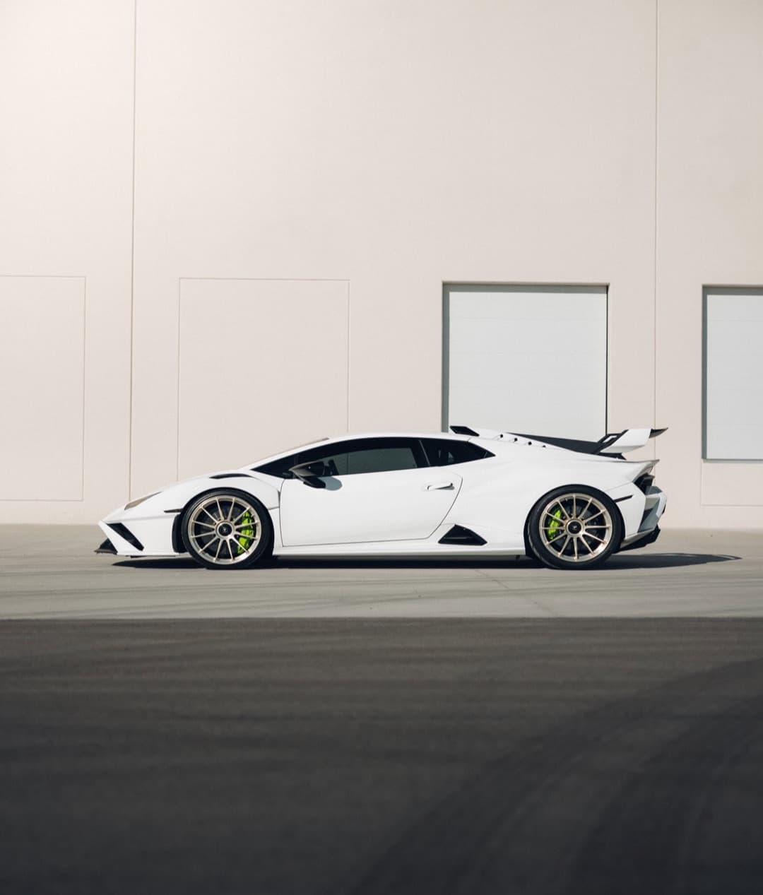 A white Lamborghini Huracan STO in profile against a cream wall