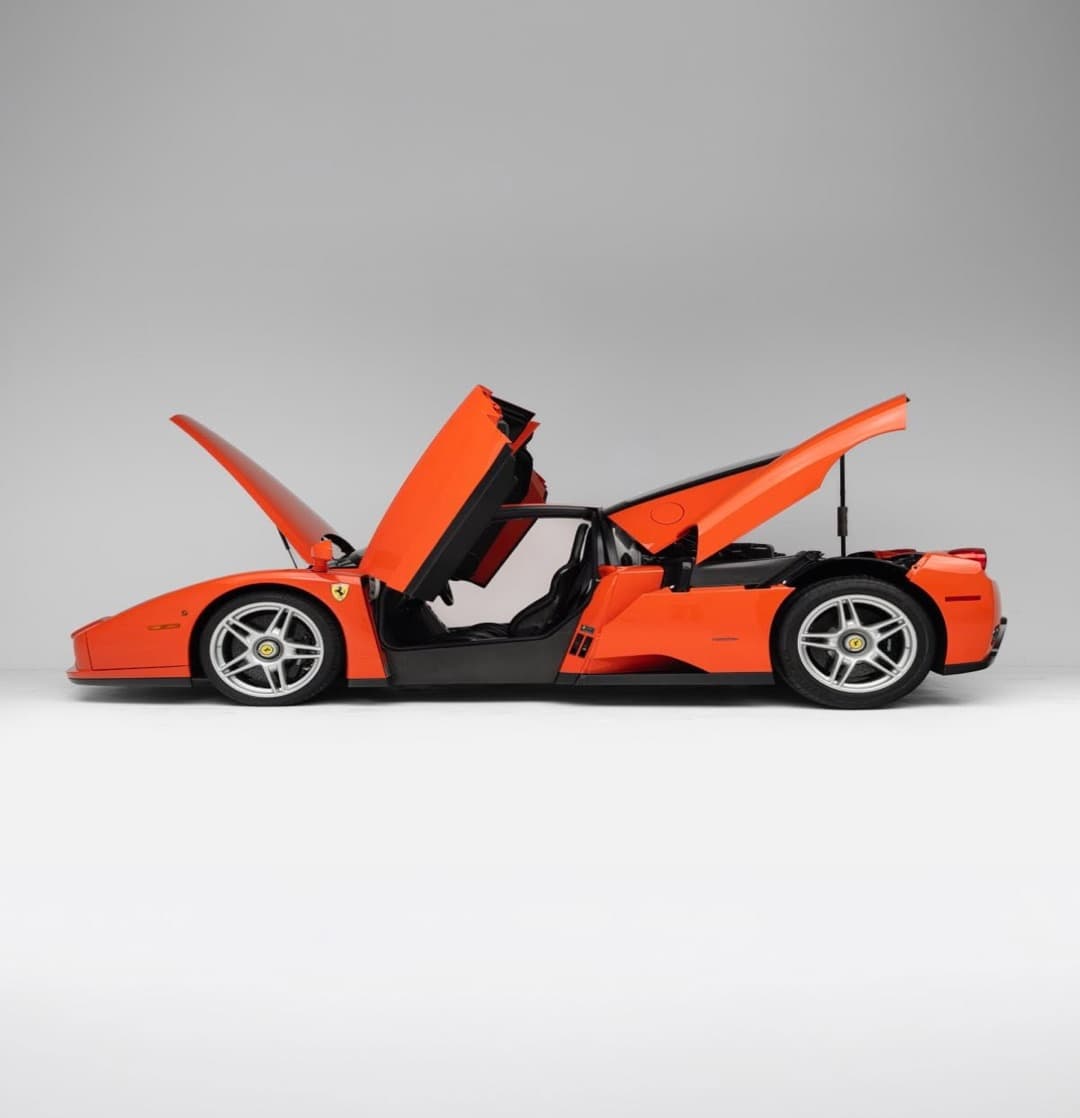 A red Ferrari Enzo in a studio with its doors and clamshells open