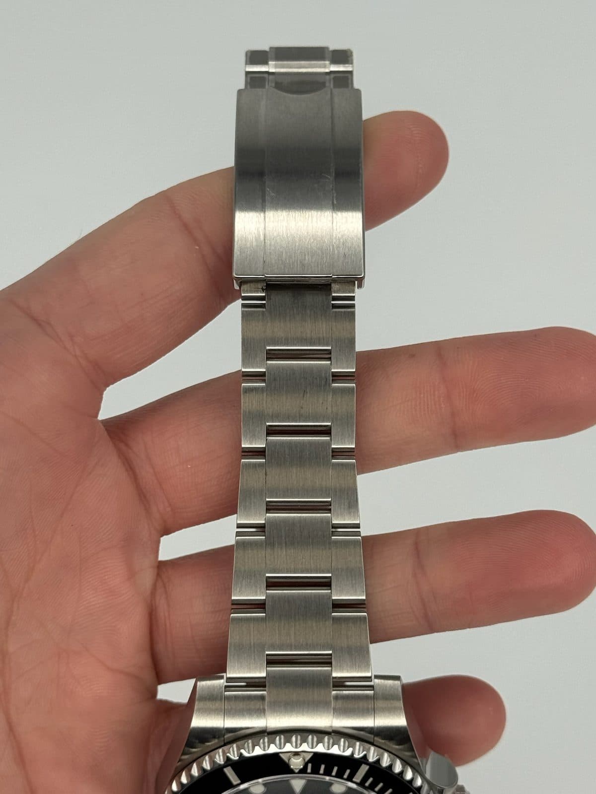 The Oyster bracelet of a Rolex Submariner 116610LN held in a hand, each row made of three links