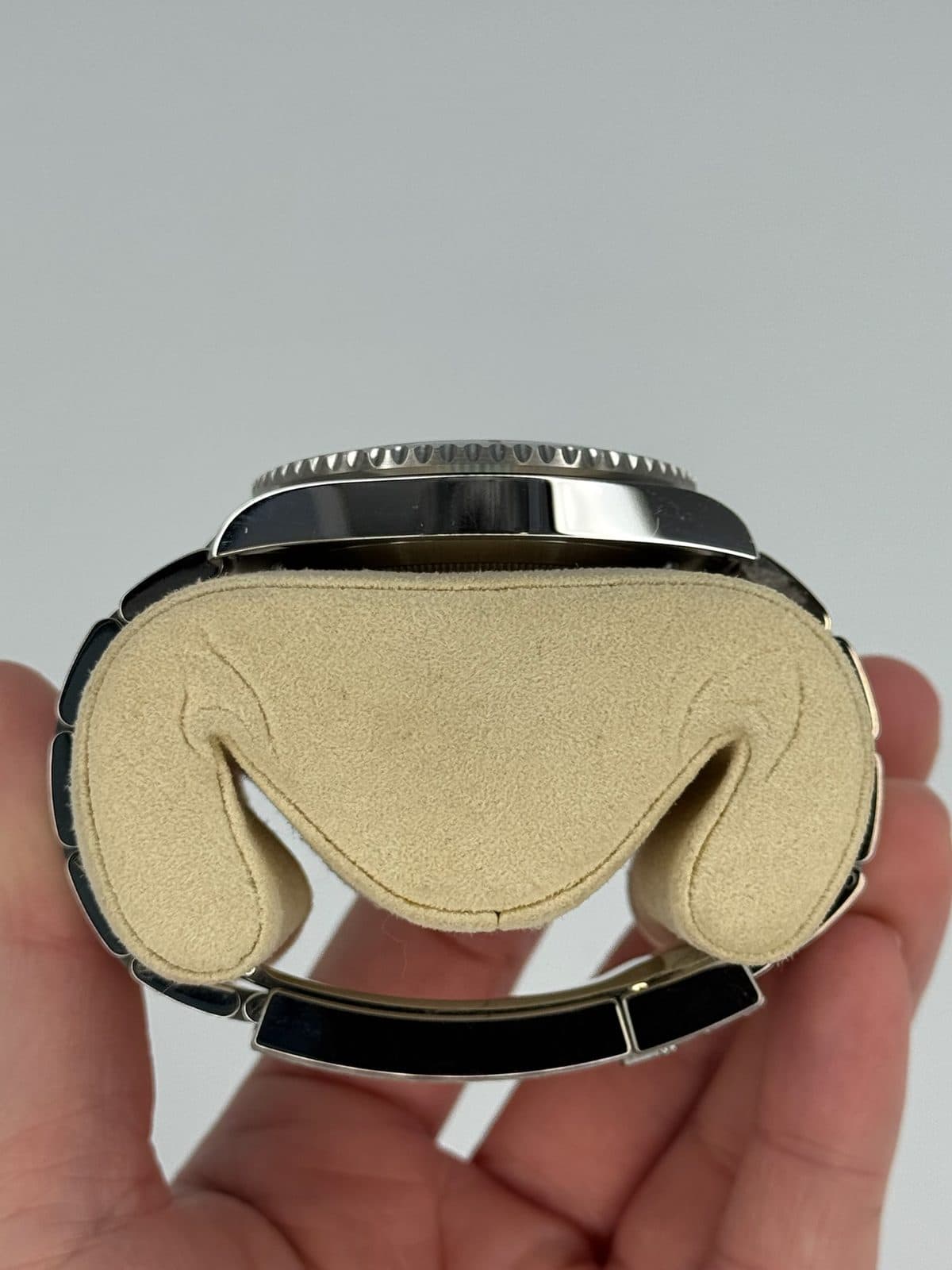 The left side of a Rolex Submariner 116610LN case on a watch pillow, showing the bezel edge and lugs